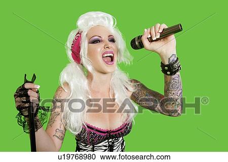 Beautiful tattooed woman singing with microphone over green background View Large Photo Image Stock Image - Beautiful tattooed woman singing with microphone over green background. Fotosearch