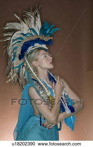 Stock Image - Beautiful woman posing in feathered outfit over colored background. Fotosearch