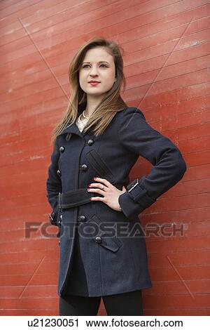 Stock Image - Beautiful young business woman standing with hands on hips looking away. Fotosearch