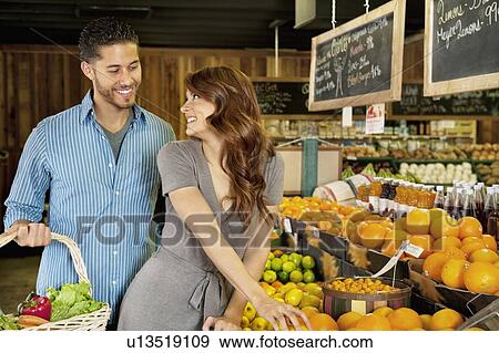 Beautiful young couple looking at each other while shopping in supermarket View Large Photo Image Stock Photo - Beautiful young couple looking at each other while shopping in supermarket. Fotosearch
