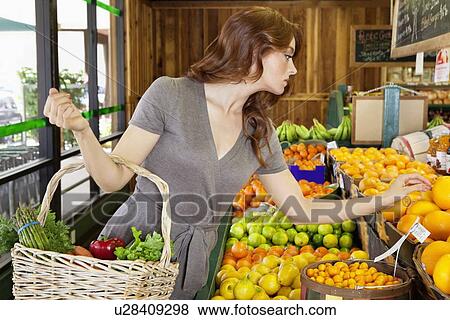 Beautiful young female shopping for fruits in market View Large Photo Image Stock Photo - Beautiful young female shopping for fruits in market. Fotosearch