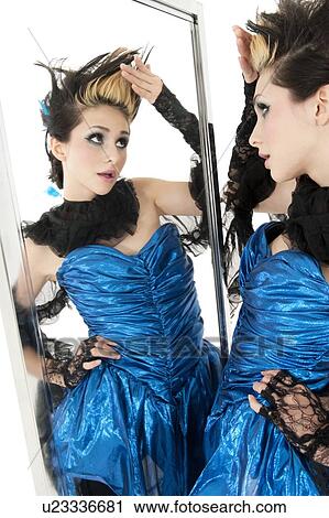 Stock Image - Beautiful young woman looking at herself in mirror. Fotosearch