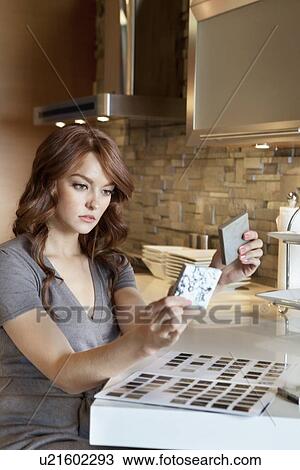 Beautiful young woman looking at tile samples in model home View Large Photo Image Stock Image - Beautiful young woman looking at tile samples in model home. Fotosearch