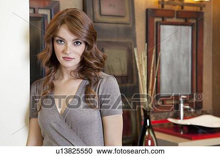 Stock Image - Beautiful young woman standing in model home. Fotosearch