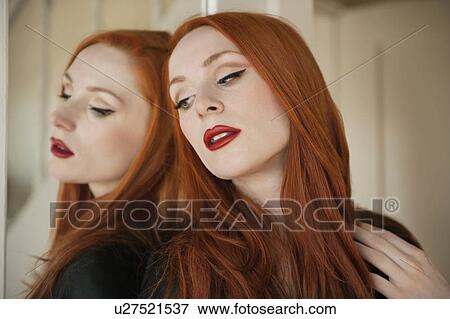 Stock Photo - Beautiful young woman with her reflection in mirror. Fotosearch