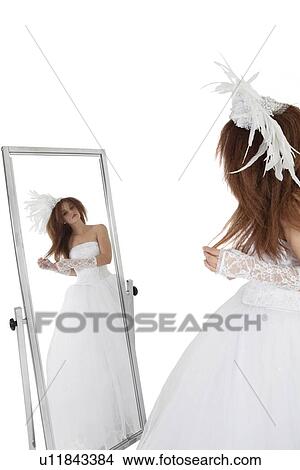 Brunette in wedding gown looking at mirror over white background View Large Photo Image Picture - Brunette in wedding gown looking at mirror over white background. Fotosearch