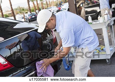 Stock Image - Car wash employee wiping rear of a vehicle. Fotosearch