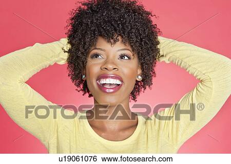 Cheerful African American looking up with hands behind head over colored background View Large Photo Image Stock Photograph - Cheerful African American looking up with hands behind head over colored background. Fotosearch