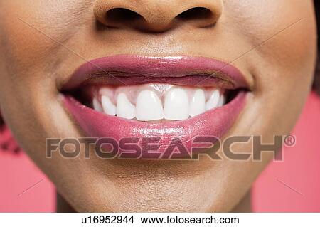 Picture - Close-up detail of an African American woman smiling over colored background. Fotosearch