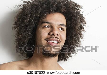 Stock Image - Close-up of a happy young man with curly hair looking away over white background. Fotosearch
