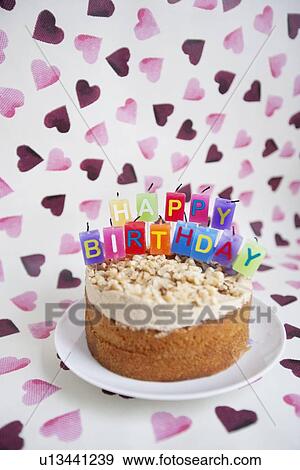 Stock Photo - Close-up of birthday cake with candles over heart shaped background. Fotosearch