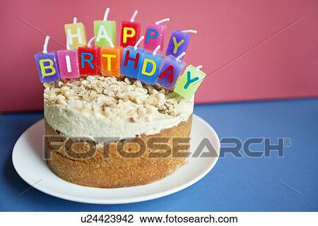 Stock Image - Close-up of birthday candles on torte cake over colored background. Fotosearch