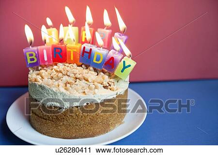 Stock Image - Close-up of candles burning on birthday cake over colored background. Fotosearch