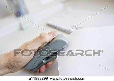 Stock Photo - Close-up of man's hand stapling paper in office. Fotosearch