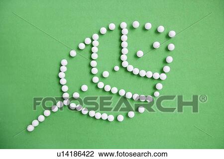 Stock Image - Close-up of push pins forming leaf over green background depicting environmentalism. Fotosearch