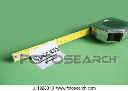 Stock Image - Close-up of sticky note stuck to measuring tape over colored background. Fotosearch