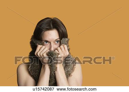 Stock Photo - Close-up of woman with fur on face looking away over colored background. Fotosearch