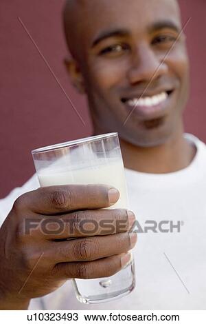 Close-up of young man holding milk glass View Large Photo Image Stock Image - Close-up of young man holding milk glass. Fotosearch