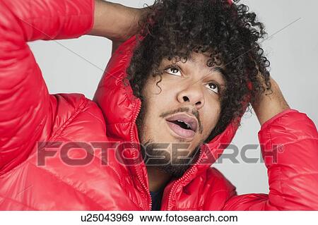 Stock Photo - Close-up of young man with curly hair looking up over colored background. Fotosearch