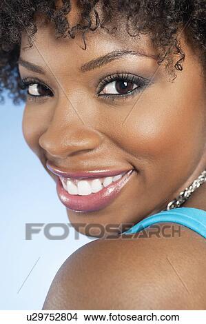 Picture - Close-up portrait of an African American woman looking back over colored background. Fotosearch