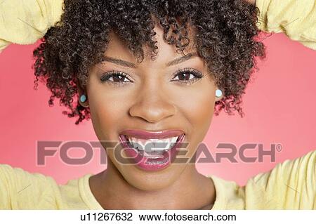 Stock Image - Close-up portrait of an African American woman smiling over colored background. Fotosearch