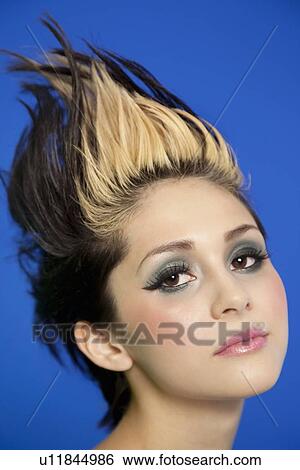 Close-up portrait of beautiful young woman with spiked hair over blue background View Large Photo Image Stock Photograph - Close-up portrait of beautiful young woman with spiked hair over blue background. Fotosearch