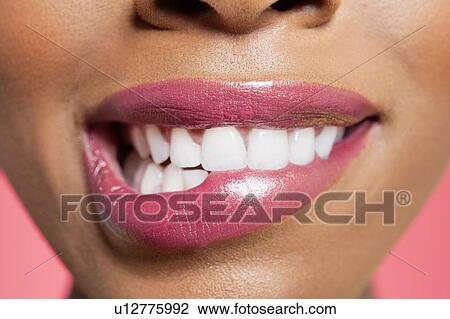 Close-up view of an female biting her lip over colored background View Large Photo Image Stock Image - Close-up view of an female biting her lip over colored background. Fotosearch
