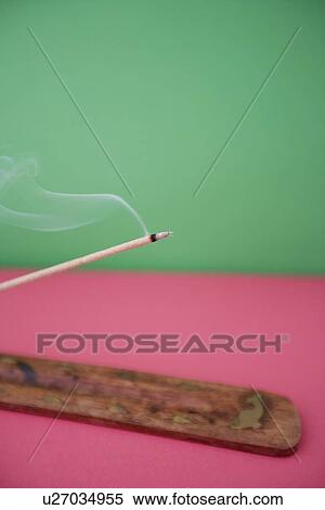 Stock Photography - Close-up view of incense stick burning over colored background. Fotosearch