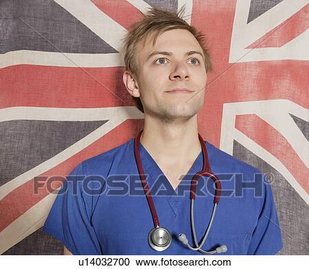 Stock Image - Confident male surgeon looking up with British Flag in background. Fotosearch