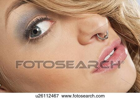 Stock Photo - Cropped image of beautiful young woman with nose ring looking sideways. Fotosearch