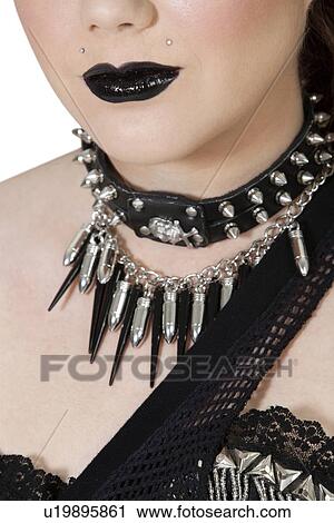 Stock Image - Cropped image of punk woman wearing bullet necklace. Fotosearch