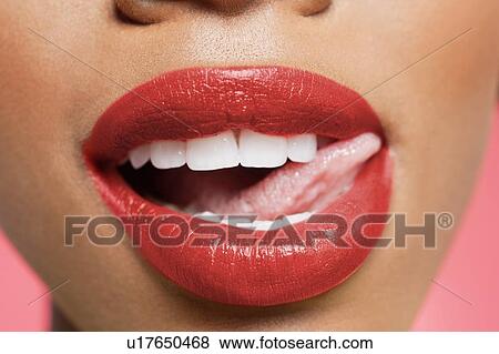 Stock Photo - Cropped image of woman licking red lipstick. Fotosearch