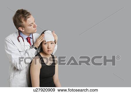 Doctor adjusting bandage on patient's head View Large Photo Image Stock Photo - Doctor adjusting bandage on patient's head. Fotosearch