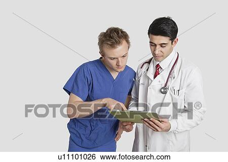 Doctor and male nurse discussing medical report over gray background View Large Photo Image Stock Photograph - Doctor and male nurse discussing medical report over gray background. Fotosearch