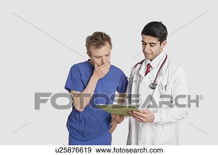 Doctor discussing medical report with male nurse over gray background View Large Photo Image Stock Photo - Doctor discussing medical report with male nurse over gray background. Fotosearch