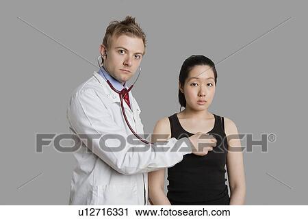 Doctor examining female patient with stethoscope View Large Photo Image Stock Image - Doctor examining female patient with stethoscope. Fotosearch