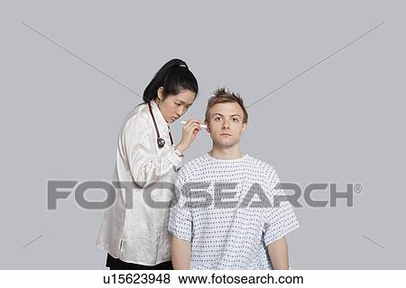 Doctor examining patient's ear with flashlight View Large Photo Image Stock Photo - Doctor examining patient's ear with flashlight. Fotosearch