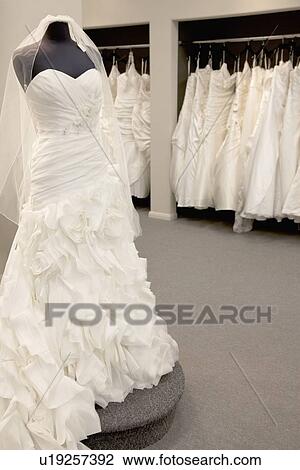 Stock Image - Elegant wedding dress displayed on mannequin in bridal store. Fotosearch