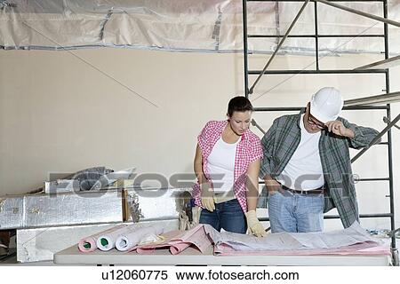 Front view of architects working at blueprints together at table View Large Photo Image Stock Photography - Front view of architects working at blueprints together at table. Fotosearch