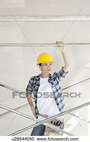 Front view of mid adult worker looking away while standing under scaffold View Large Photo Image Stock Image - Front view of mid adult worker looking away while standing under scaffold. Fotosearch