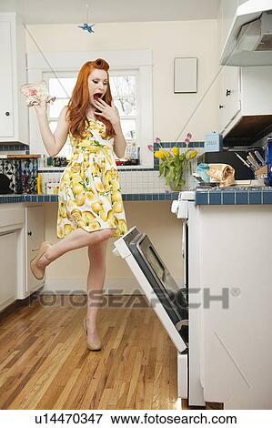 Stock Photo - Full length of a terrified young woman looking at open oven. Fotosearch