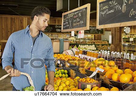 Handsome young man shopping for fruits in market View Large Photo Image Picture - Handsome young man shopping for fruits in market. Fotosearch