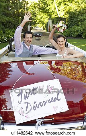 Stock Image - Happy couple in a convertible car waving with just divorced sign on it. Fotosearch