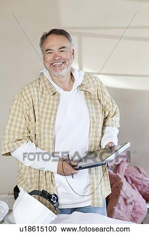 Stock Image - Happy male architect holding digital tablet pc at construction site. Fotosearch