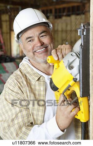 Happy mature male construction worker cutting wood with a circular saw View Large Photo Image Stock Photograph - Happy mature male construction worker cutting wood with a circular saw. Fotosearch