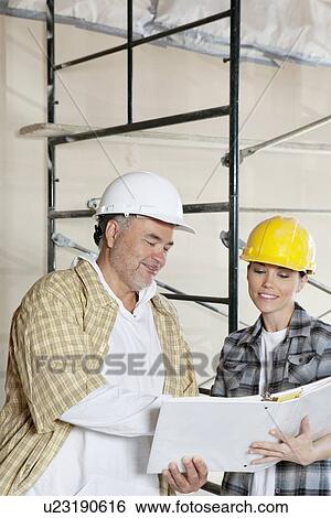 Happy team of architects looking at paper View Large Photo Image Stock Photograph - Happy team of architects looking at paper. Fotosearch