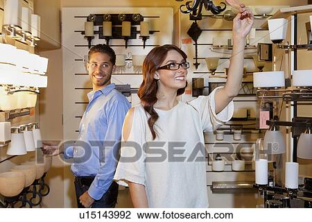 Stock Image - Happy young couple browsing for fixtures in lights store. Fotosearch
