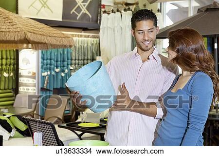 Happy young couple looking at each other while man holding a souvenir in store View Large Photo Image Picture - Happy young couple looking at each other while man holding a souvenir in store. Fotosearch