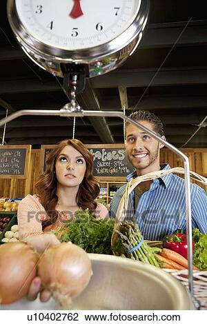 Happy young couple looking at weight scale in supermarket View Large Photo Image Stock Image - Happy young couple looking at weight scale in supermarket. Fotosearch