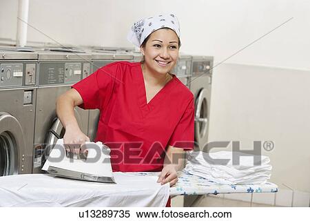 Happy young employee wearing bandana while ironing in Laundromat View Large Photo Image Stock Photography - Happy young employee wearing bandana while ironing in Laundromat. Fotosearch